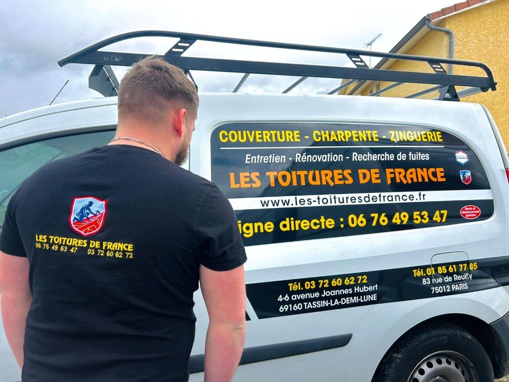 Artisan des Toitures de France devant le véhicule de l'entreprise