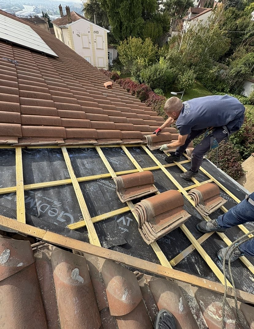 Couvreur posant des tuiles neuves sur liteaux et écran sous toiture