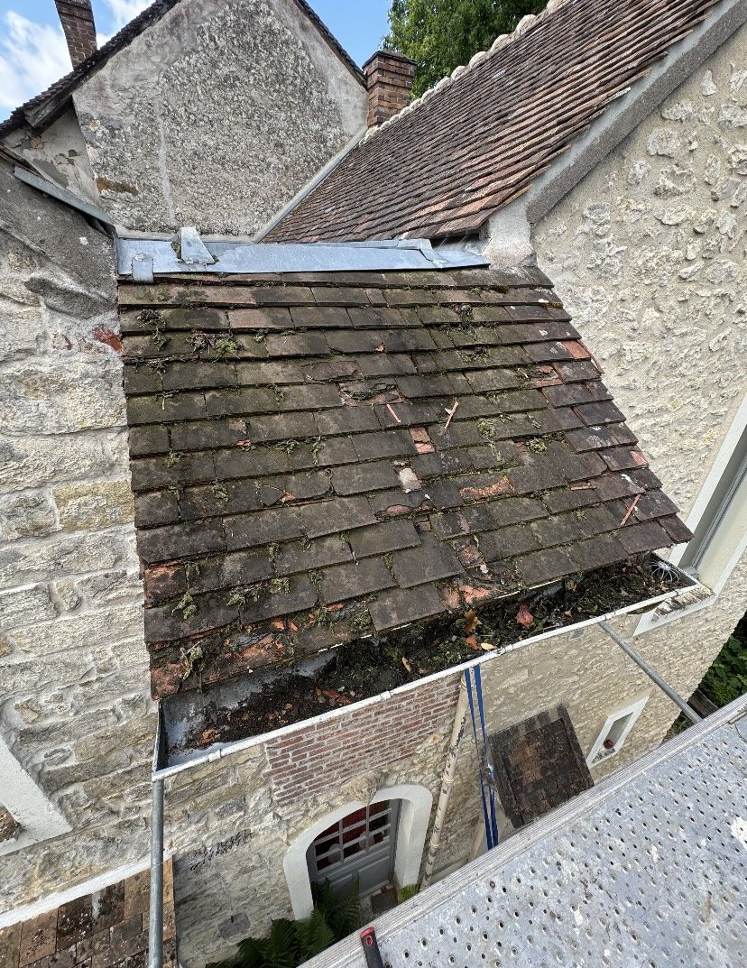 Ancienne toiture en tuiles couverte de mousse avant réfection